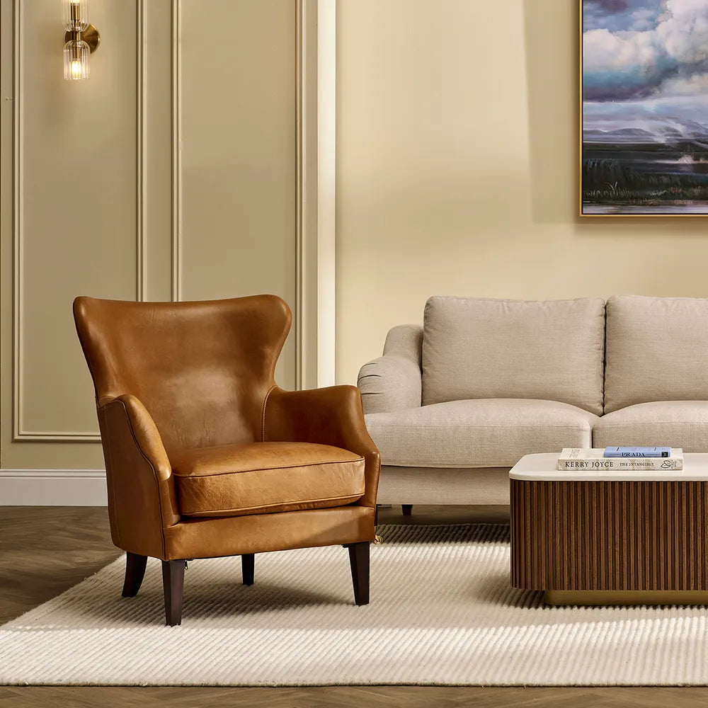 Brown leather armchair and beige sofa in a living room setting with a coffee table and wall art.