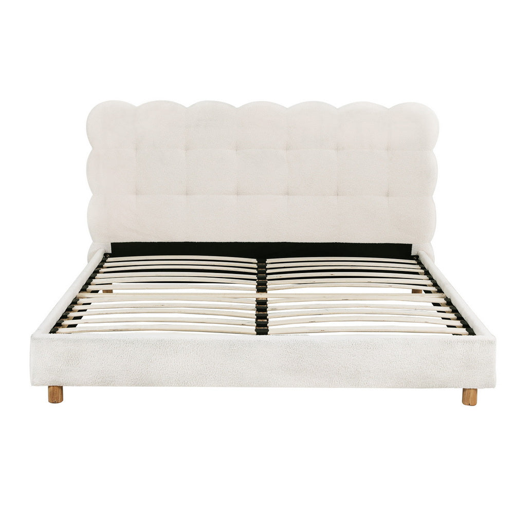 White upholstered bed with scalloped headboard on a white background