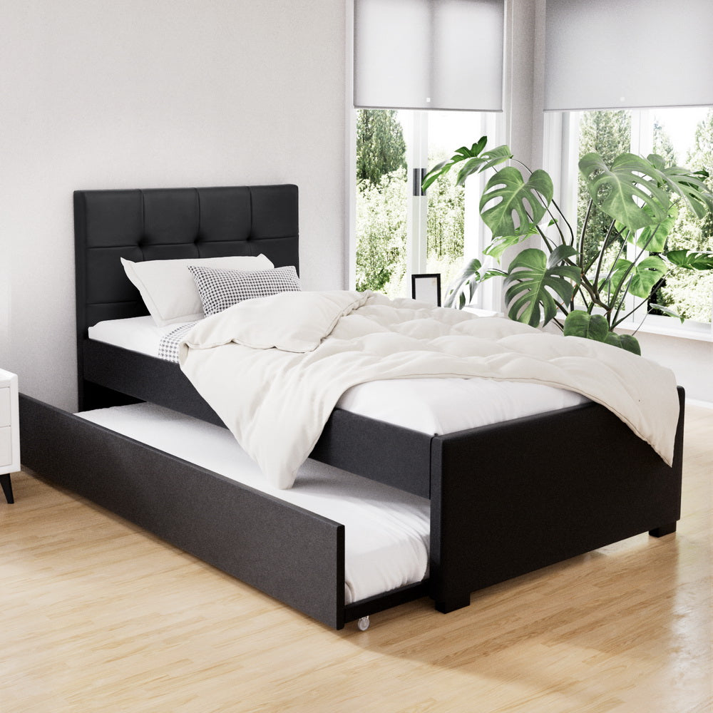 Black bed frame with white bedding in a bright room with plants