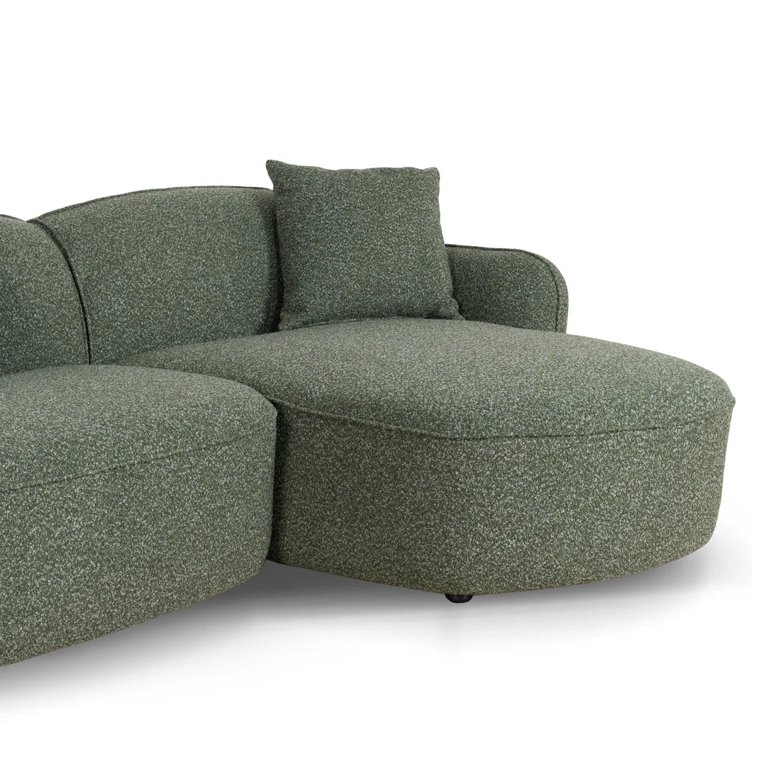 Green textured sectional sofa with a pillow on a white background