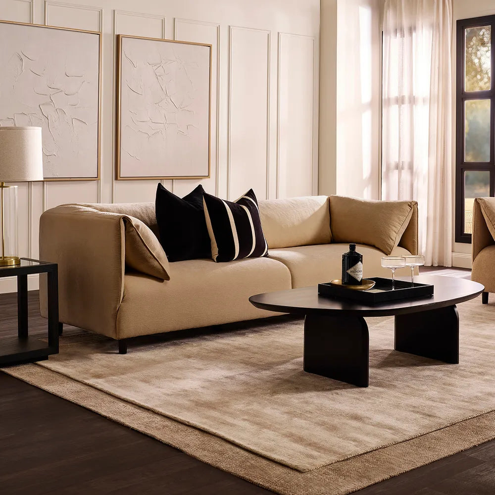 Modern living room with beige sofa, black coffee table, and decorative pillows.